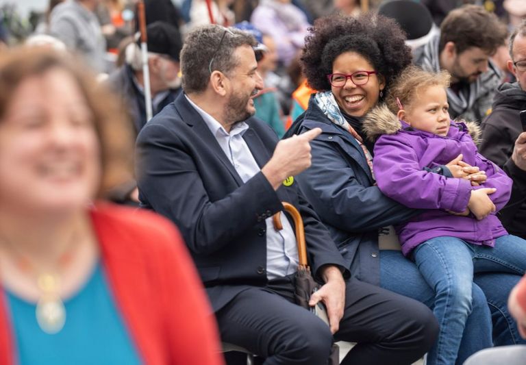 Due persone tra il pubblico parlano durante un grande evento sulla piazza federale